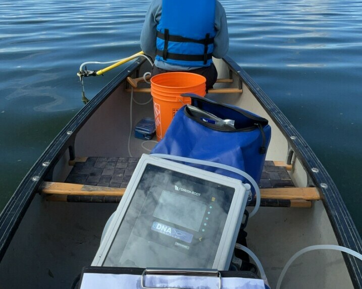 Inside of canoe shows screen and paper pad with another canoeist in the background.