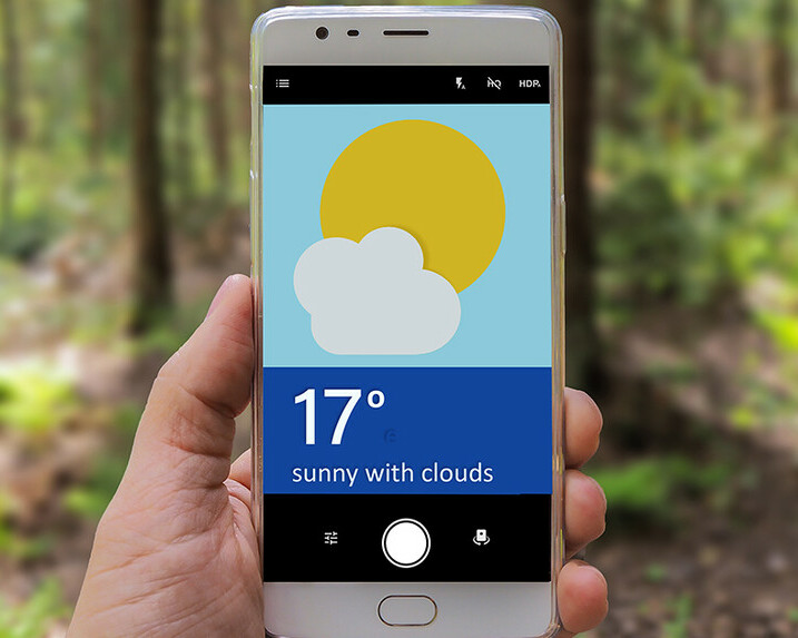 Hand holds up smartphone with a weather forecast app on the screen.