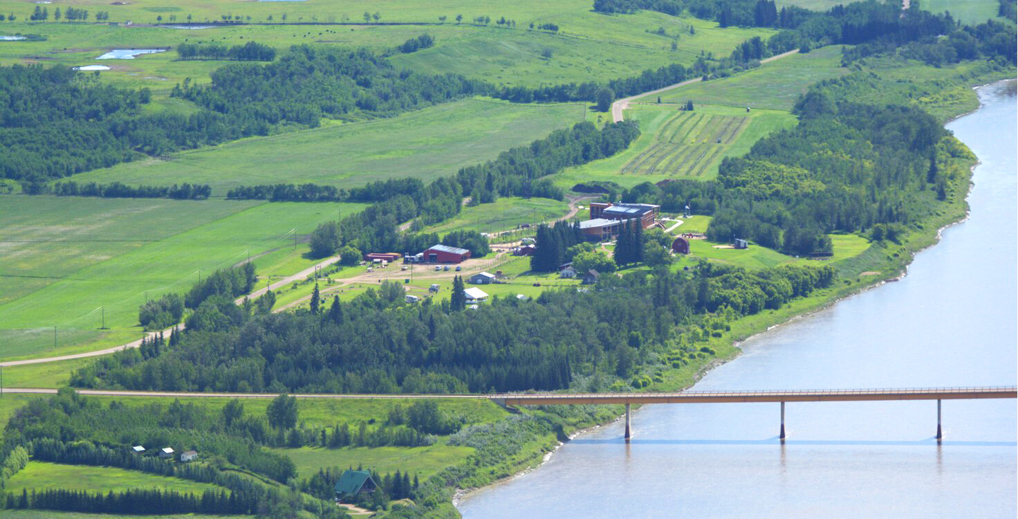 Aerial shot of Metis Crossing with lush green landscape and bridge crossing the North Saskatchewan River.